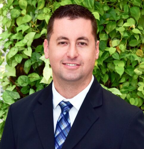 Professional man in suit with green leafy background.