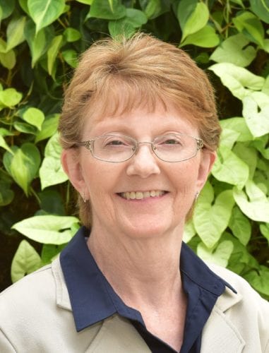 Smiling elderly woman with glasses outdoors.