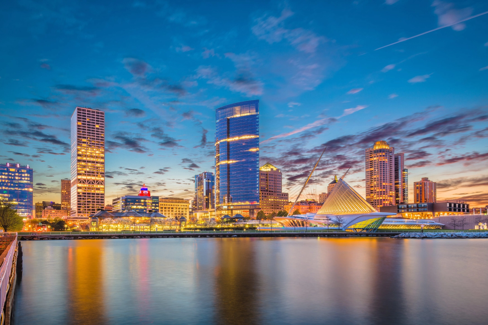 City skyline at dusk reflecting on calm water.