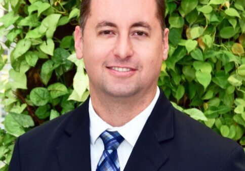 Professional man in suit with green leafy background.