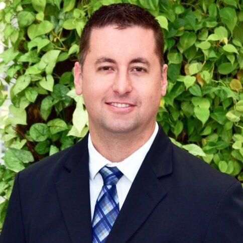 Professional man in suit with green leafy background.